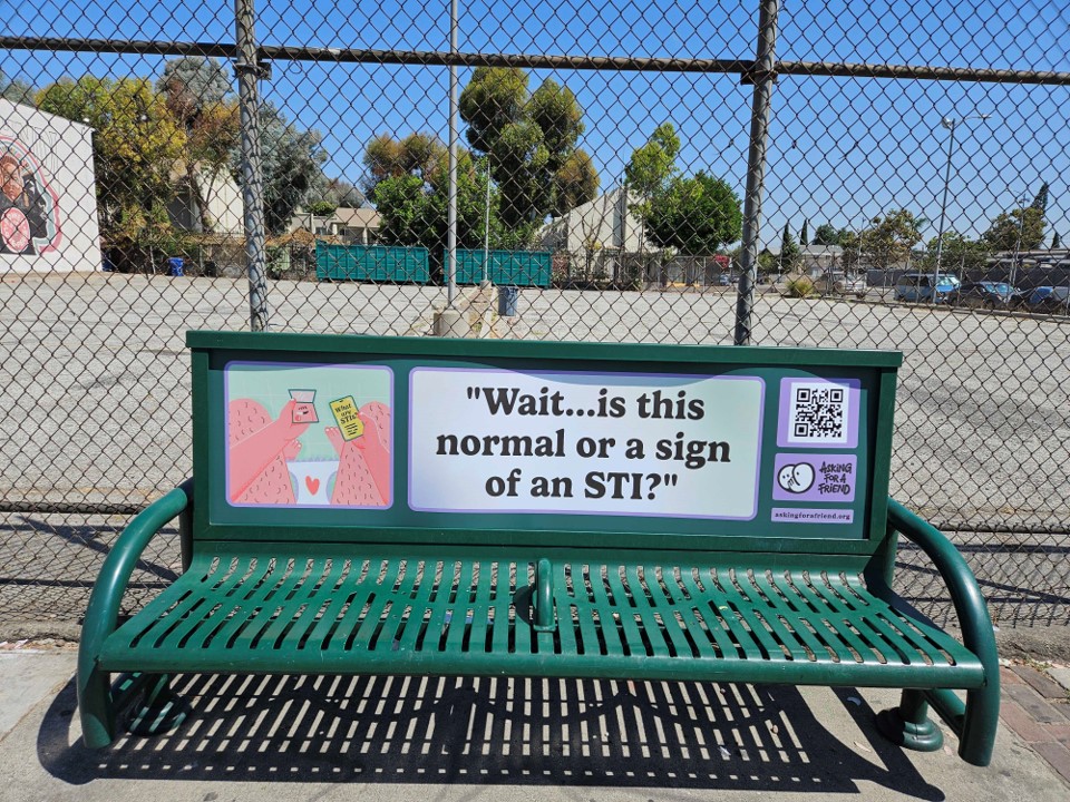 A public bench advertisement for STI awareness featuring the phrase "Wait...is this normal or a sign of an STI?" with a QR code linking to sexual health resources by AskingForAFriend.org